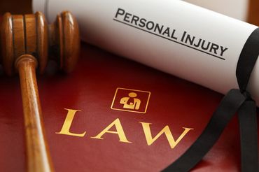 Gavel beside a red law book and a white card labeled “PERSONAL INJURY”